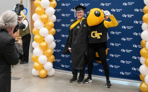 Student posing with Buzz at the President's Graduation Celebration
